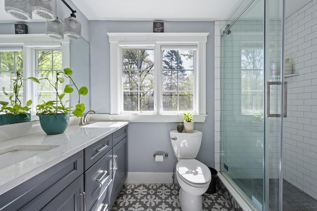 bathroom featuring healthy amount of natural light, toilet, a stall shower, and double vanity
