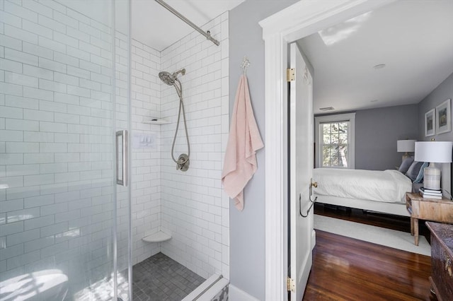 full bath with ensuite bath, a shower stall, wood finished floors, and baseboards