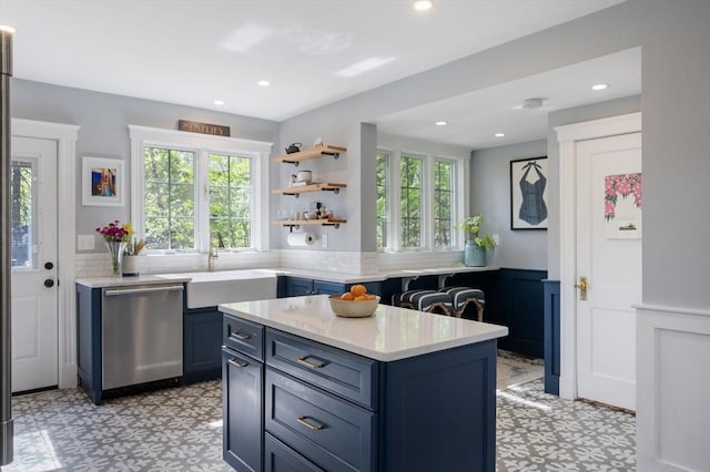 kitchen with stainless steel dishwasher, light floors, healthy amount of natural light, wainscoting, and recessed lighting