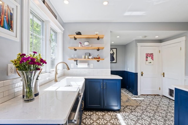 kitchen with blue cabinetry, a sink, a wainscoted wall, backsplash, and recessed lighting