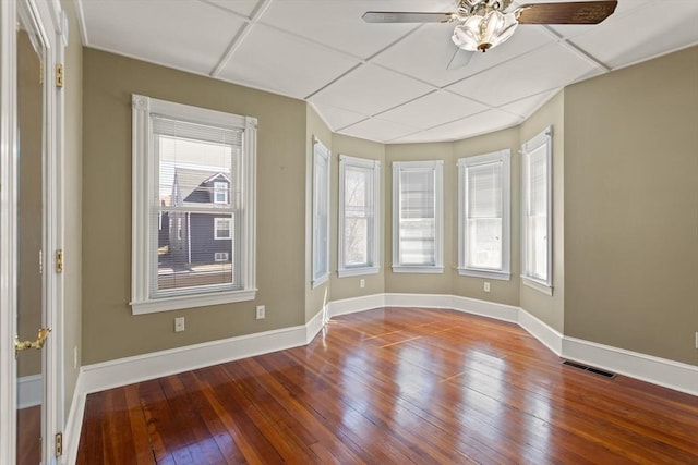 empty room with a wealth of natural light, visible vents, baseboards, and hardwood / wood-style flooring