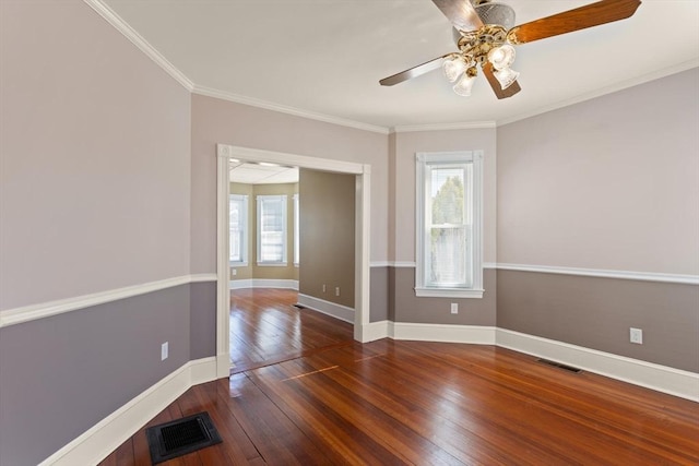 empty room with visible vents, baseboards, ornamental molding, and hardwood / wood-style flooring