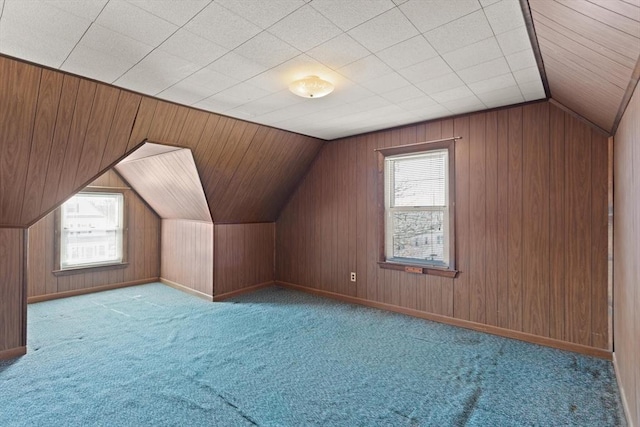 additional living space with baseboards, wood walls, carpet flooring, and vaulted ceiling