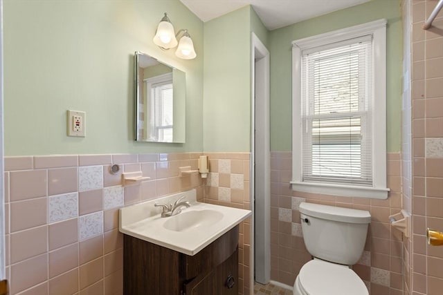 bathroom featuring vanity, tile walls, toilet, and wainscoting