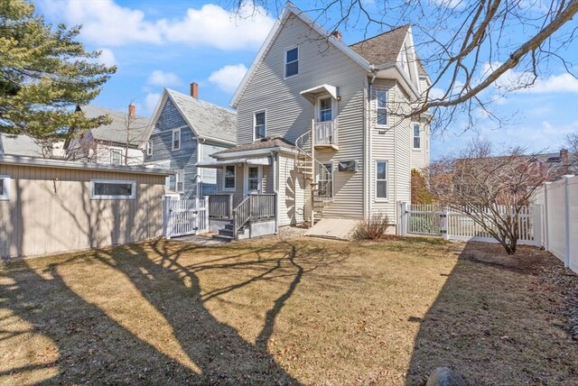 back of house featuring fence, a yard, and a gate