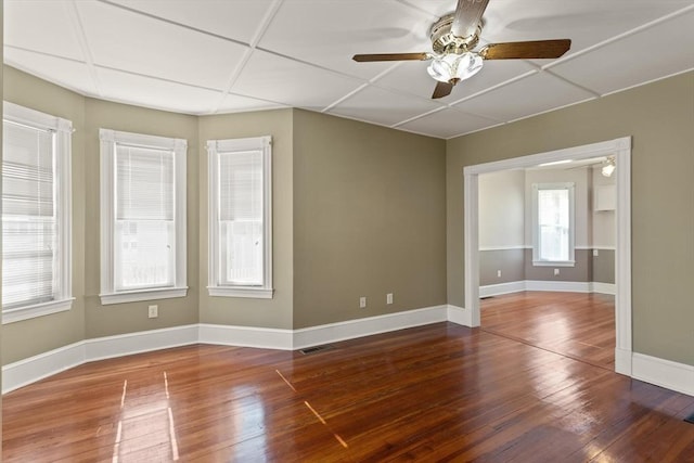 spare room with baseboards, visible vents, ceiling fan, hardwood / wood-style flooring, and a paneled ceiling