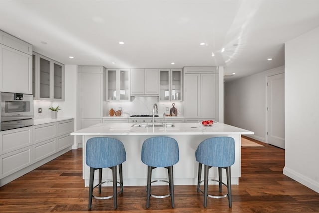 kitchen with dark wood finished floors, a kitchen bar, a sink, and oven