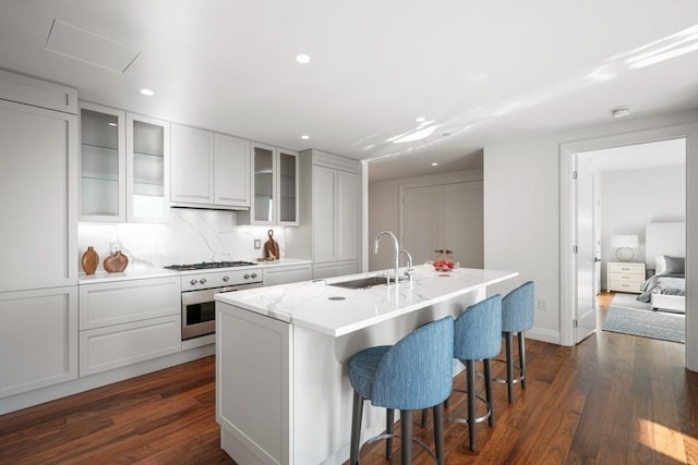 kitchen with oven, dark wood-type flooring, white gas cooktop, a sink, and a kitchen breakfast bar