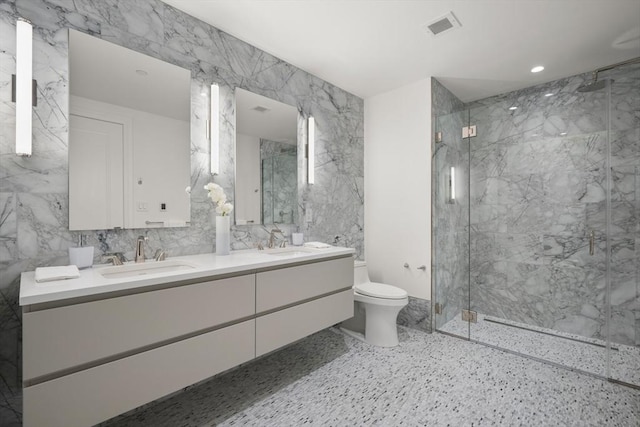 full bathroom featuring toilet, a marble finish shower, a sink, and visible vents