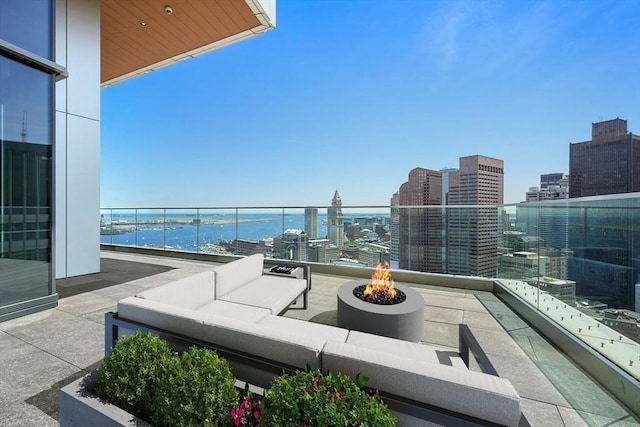 view of patio featuring a water view, a balcony, a city view, and an outdoor living space with a fire pit