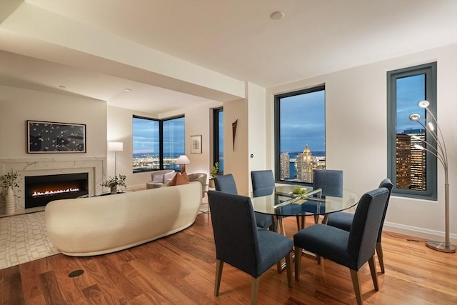 dining room featuring light wood-style floors, a fireplace, and baseboards