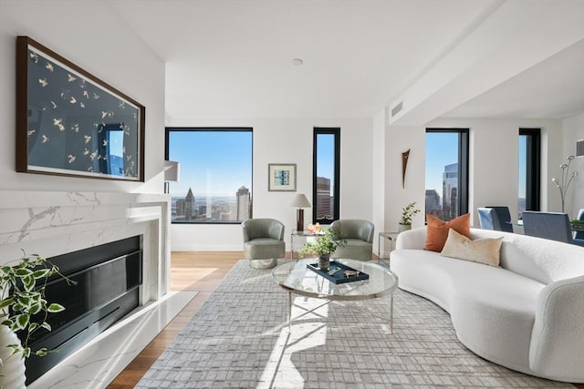 living area featuring a high end fireplace, visible vents, a view of city, and wood finished floors