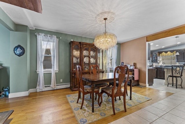 dining area with a notable chandelier, light hardwood / wood-style floors, sink, and baseboard heating