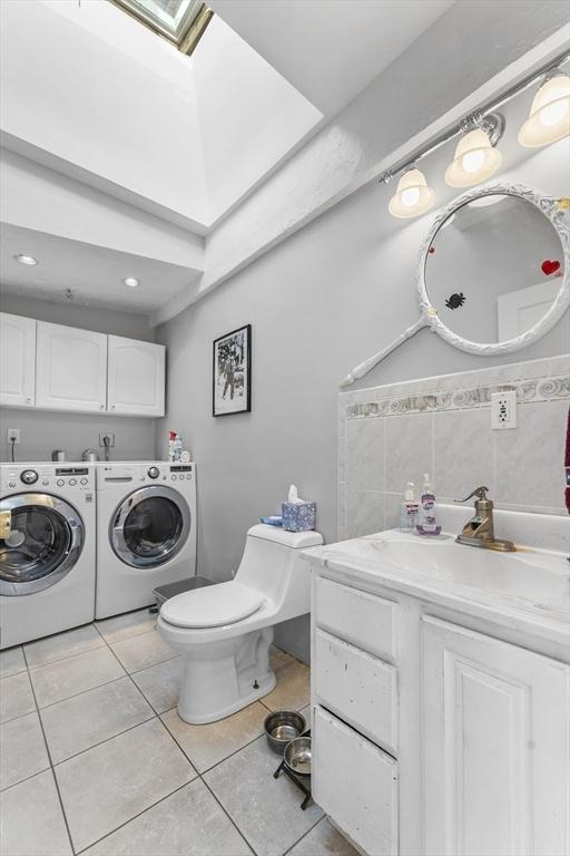 bathroom featuring tile patterned flooring, vanity, washer and dryer, and toilet