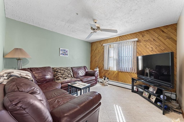 carpeted living room featuring baseboard heating, ceiling fan, wooden walls, and a textured ceiling