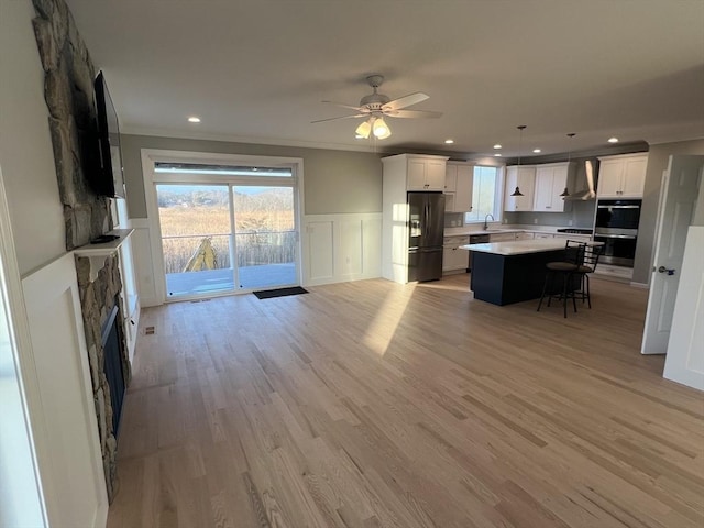 living room featuring a fireplace, light hardwood / wood-style flooring, ceiling fan, and crown molding