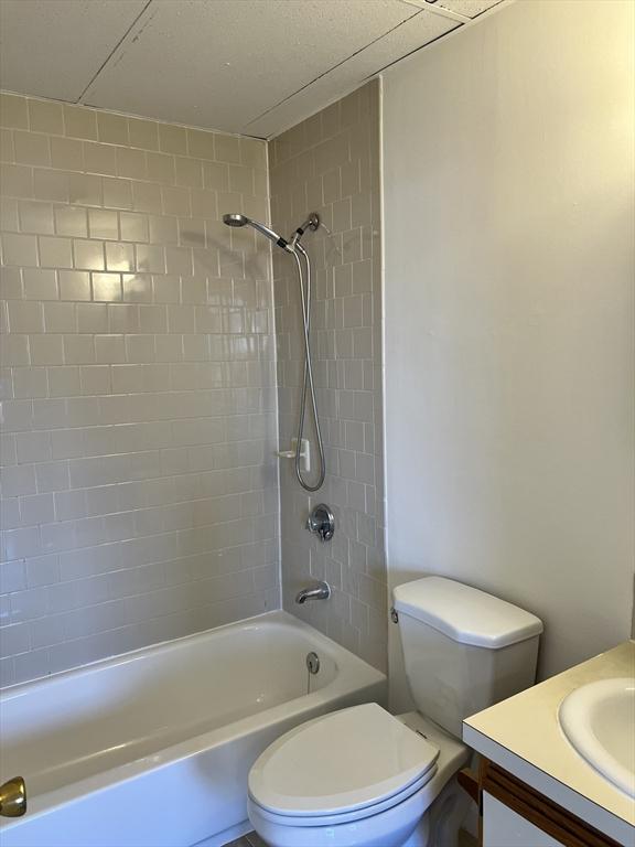 bathroom featuring toilet, vanity, and shower / tub combination