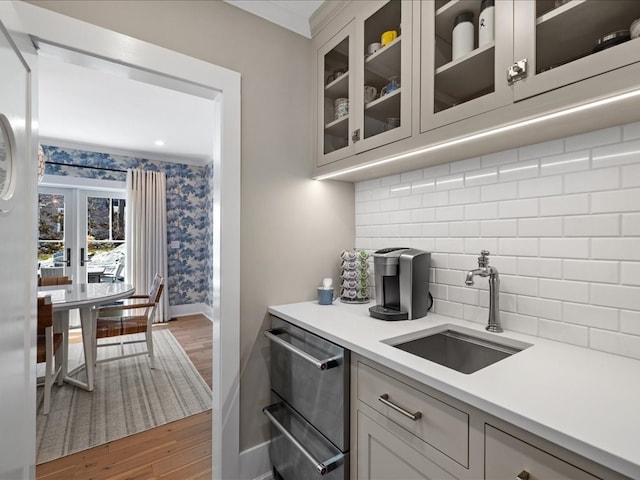 kitchen featuring sink, backsplash, white cabinets, crown molding, and dark wood-type flooring