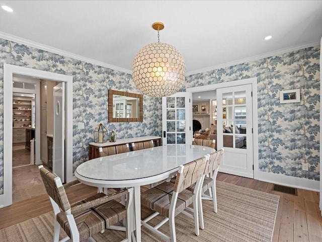 572 Jerusalem Rd, Cohasset, MA 02025 - dining room featuring wood-type flooring, ornamental molding, wallpapered walls, baseboards, and french doors