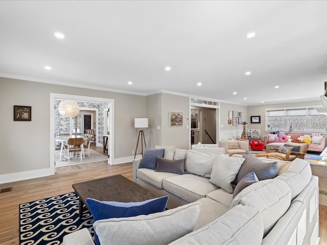 living room with ornamental molding, an inviting chandelier, and light hardwood / wood-style floors