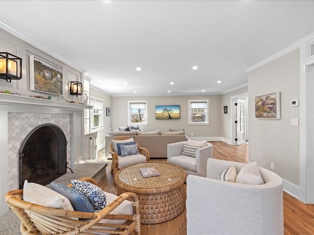 living room with light hardwood / wood-style floors, a tile fireplace, a healthy amount of sunlight, and crown molding