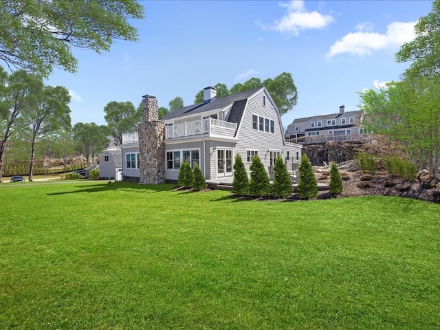 back of property with a lawn and a balcony