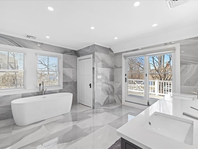 bathroom with a wealth of natural light, vanity, and a tub