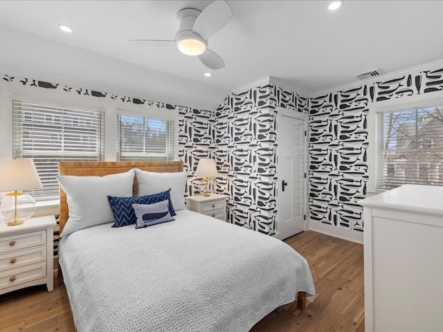 bedroom with hardwood / wood-style flooring, ceiling fan, and multiple windows