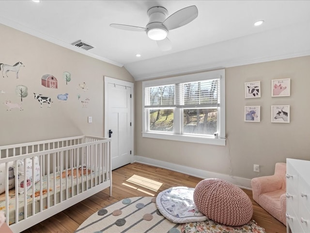 bedroom featuring a nursery area, wood-type flooring, ceiling fan, and lofted ceiling