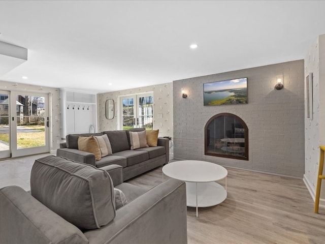 living room with a brick fireplace and light wood-type flooring