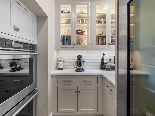 interior space featuring stainless steel double oven, tasteful backsplash, and white cabinetry