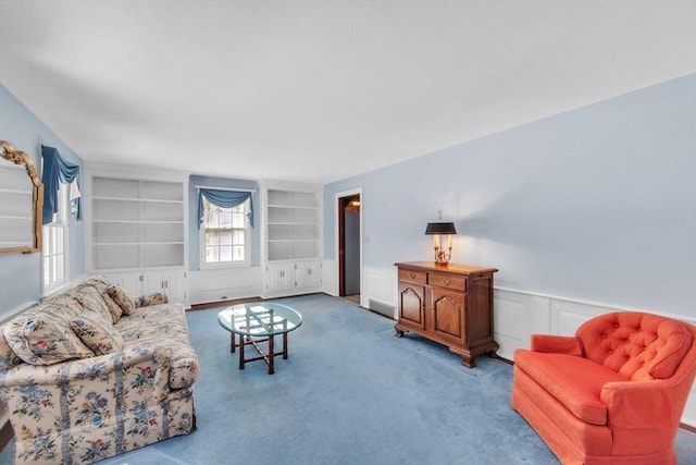 living area with built in shelves, carpet, a wainscoted wall, and a decorative wall