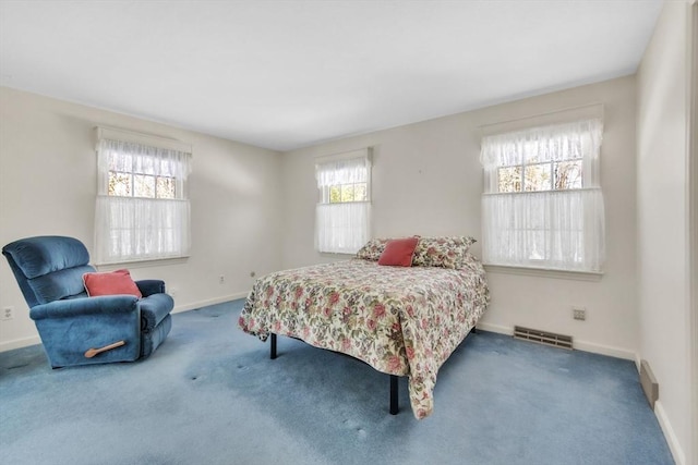 bedroom with carpet floors, baseboards, multiple windows, and visible vents