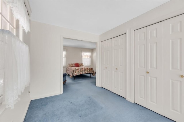 unfurnished bedroom featuring carpet floors, baseboards, and two closets