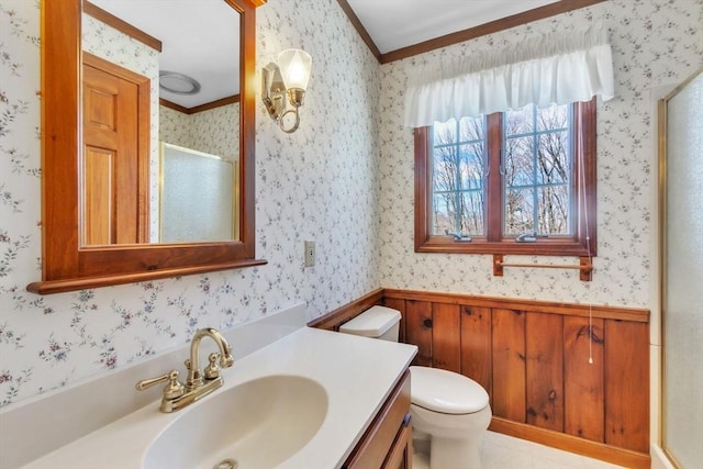 bathroom featuring toilet, wainscoting, a shower stall, vanity, and wallpapered walls