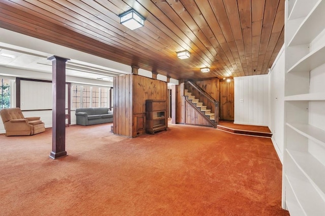 unfurnished living room with wooden walls, wood ceiling, stairway, carpet floors, and ornate columns