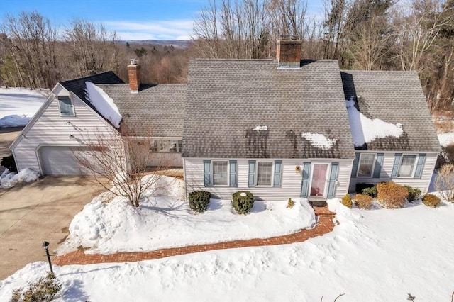 view of front of home with concrete driveway, a shingled roof, and a chimney