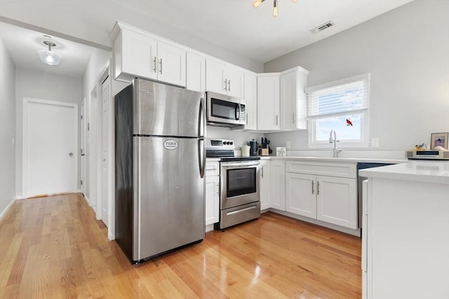 162 Willow Rd Unit 11, Nahant, MA 01908 - kitchen featuring appliances with stainless steel finishes, light wood-style flooring, white cabinetry, and light countertops