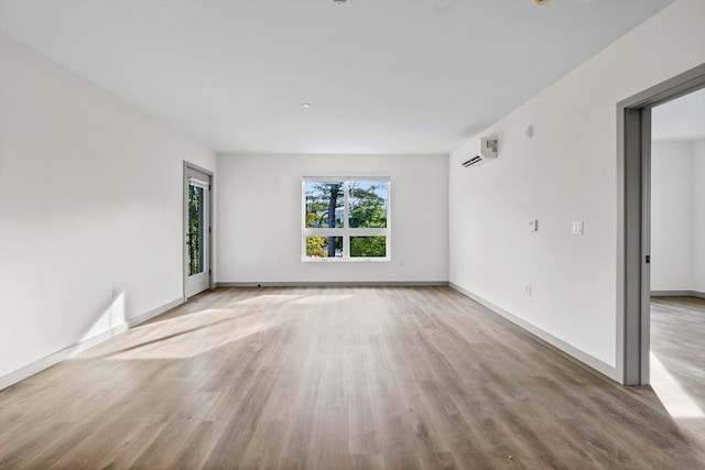 empty room featuring hardwood / wood-style flooring and a wall mounted AC