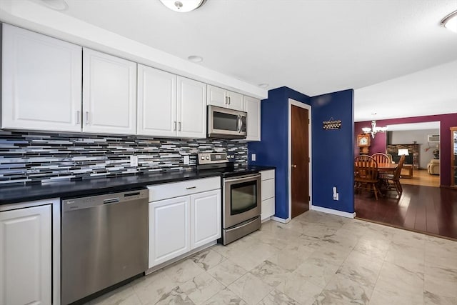 kitchen with dark countertops, white cabinets, appliances with stainless steel finishes, and tasteful backsplash