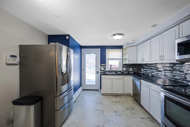 kitchen with dark countertops, a sink, appliances with stainless steel finishes, marble finish floor, and open shelves