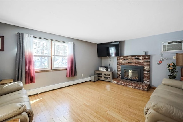 living room featuring a baseboard heating unit, wood finished floors, a wall unit AC, baseboards, and a brick fireplace