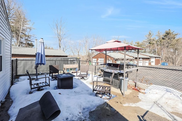 snow covered patio featuring a fire pit and fence