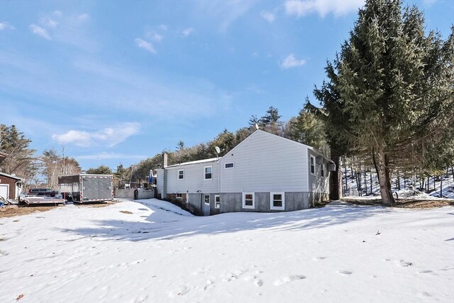 snow covered back of property with a garage and a trampoline