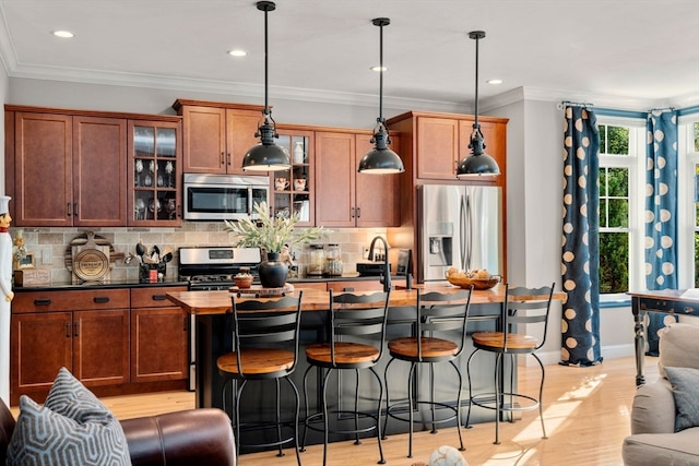 kitchen featuring light hardwood / wood-style flooring, hanging light fixtures, stainless steel appliances, and backsplash