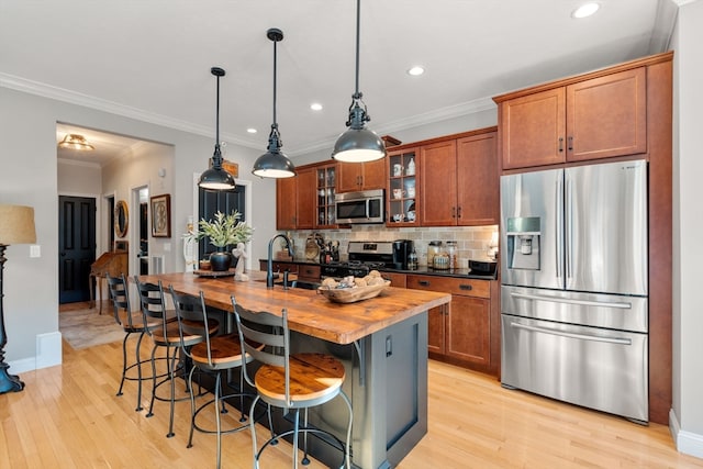 kitchen with stainless steel appliances, wood counters, light hardwood / wood-style flooring, and a kitchen island with sink