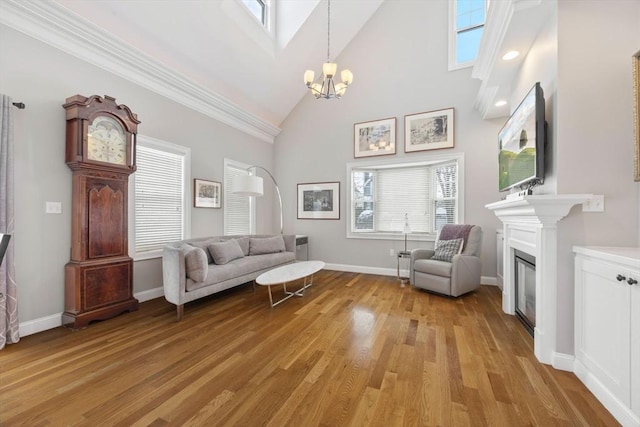 unfurnished room featuring a high ceiling, a chandelier, light wood-type flooring, and ornamental molding