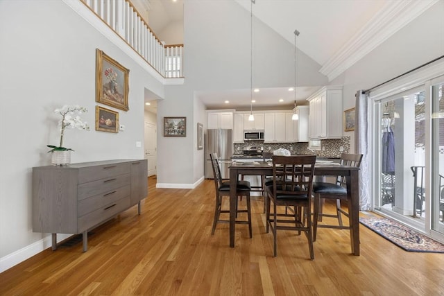 dining area with high vaulted ceiling, light hardwood / wood-style floors, and crown molding