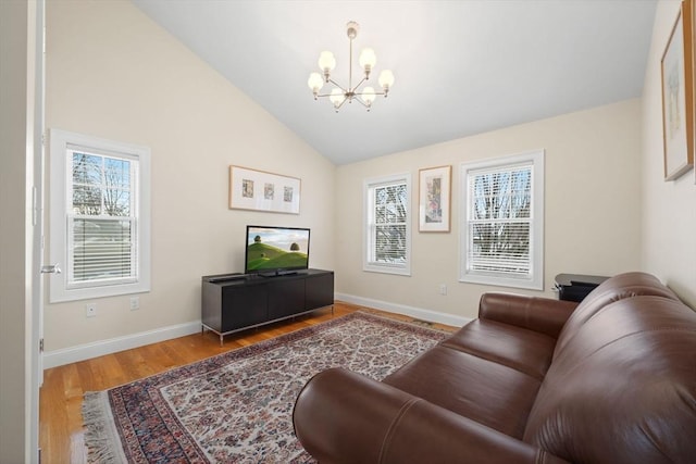 living room with hardwood / wood-style flooring, an inviting chandelier, high vaulted ceiling, and plenty of natural light