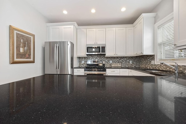 kitchen featuring stainless steel appliances, white cabinetry, sink, and tasteful backsplash